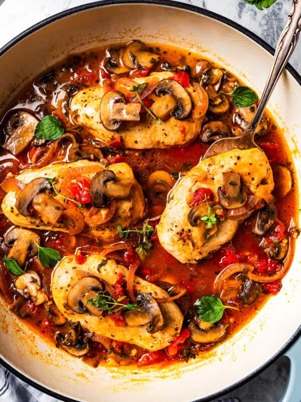 Overhead view of chicken chasseur in a pot and garnished with fresh herbs.