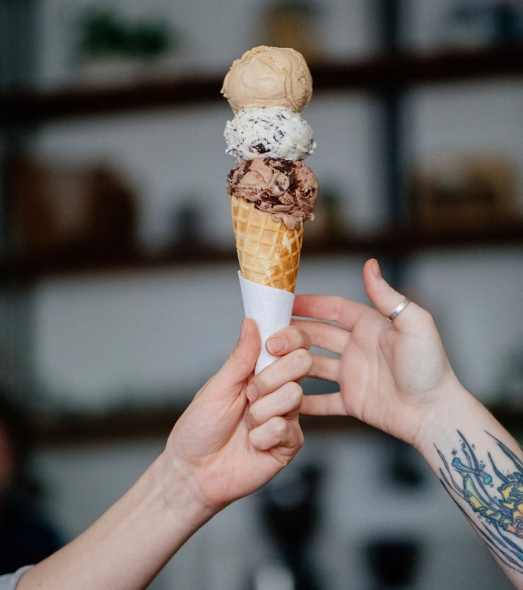 Ice cream cone being handed to someone as a gift - three scoops.