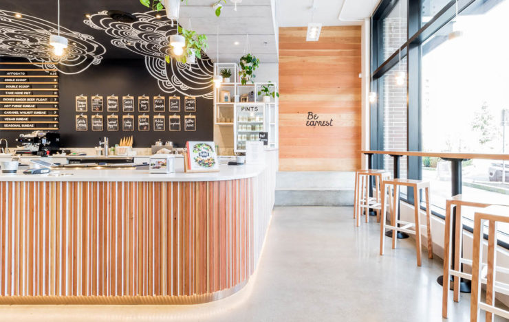 Interior of North Vancouver Earnest Ice Cream scoop shop. Wood-clad service counter and stools by the window.