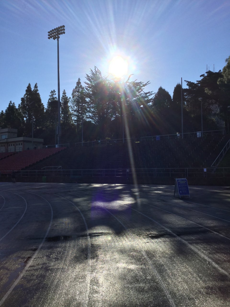 Kezar track rounding the last corner, the sun shining directly overhead lighting up track, a Covid warning placard on the edge of the lanes.