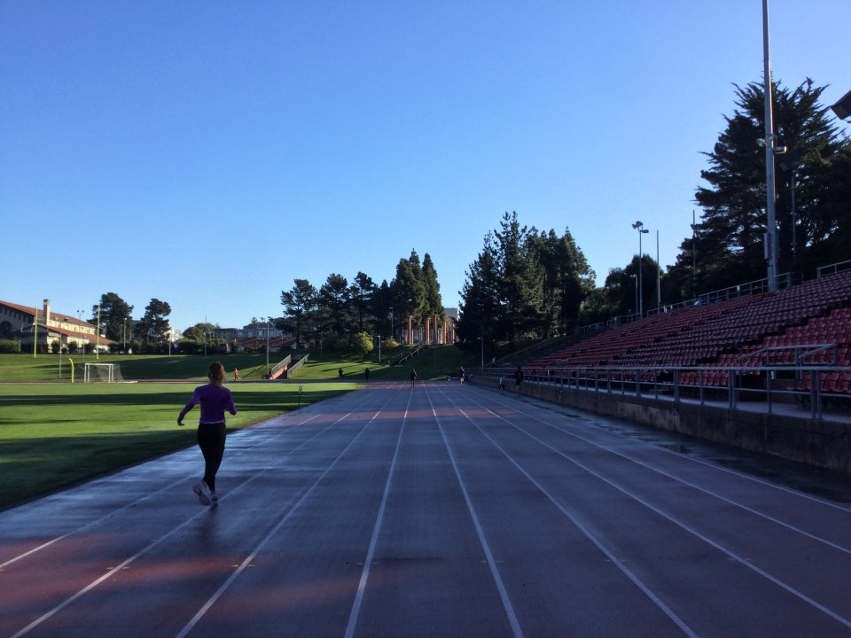 Kezar track viewed from lane 5 on the front 100meter segment, lanes 1-3 wet from rain, a runner in lane 2.