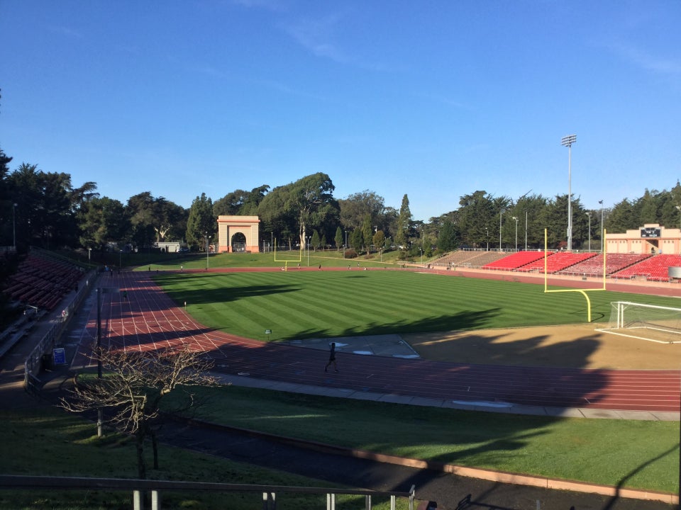 View of Kezar Stadium from the entrance, clear blue sky above, dry track below with very few runners.