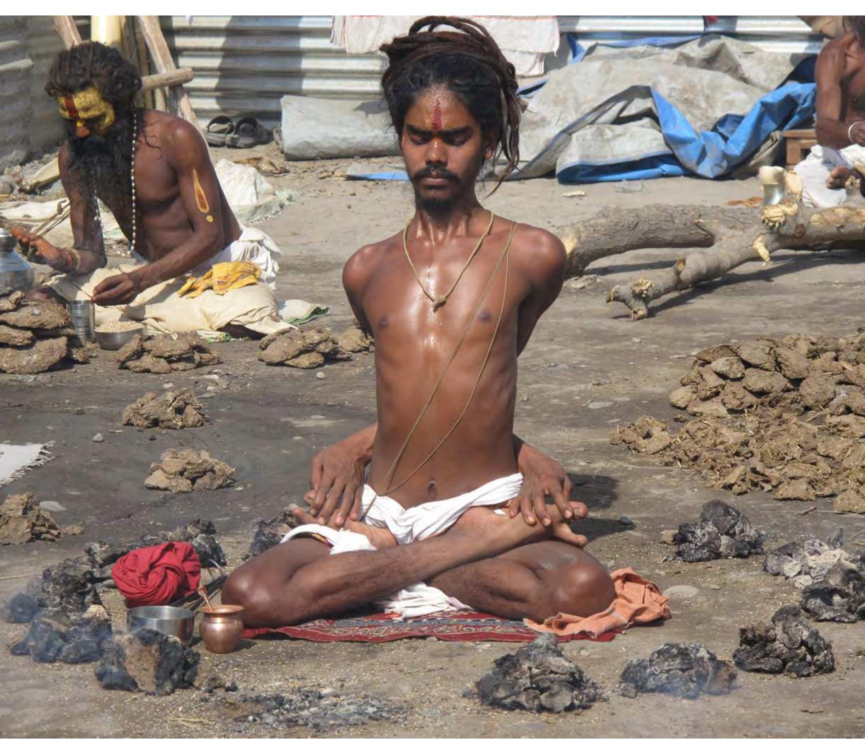 An Ascetic in Bound Lotus Sitting in a Circle of Smouldering Fires.  Some physically demanding postures probably derive from ancient ascetic traditions. For example, Bound Lotus pose (baddhapadmasana) is described in some of the ear- liest Hatha texts (e.g., Vivekamartanda 8, Gorakgasataka 59-60, Hathapradipika 1.46) as well as more recent ones. However, extreme acts of asceticism such as sitting amid smouldering cow dung fires are not included among the practices of medieval Hatha texts. Photo: James Mallinson, Haridvar, 2010 