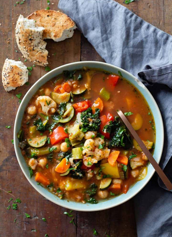 Vegetable Soup made in the instant pot in a blue bowl on a wooden table and bread and a napkin next to the bowl