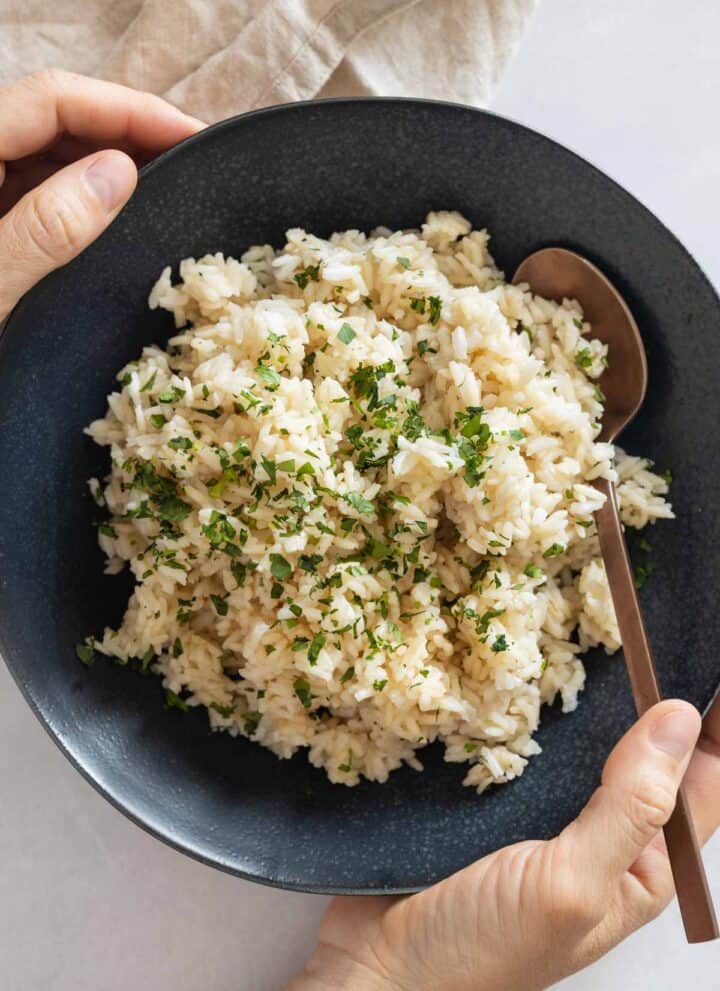 Coconut Rice in a blue bowl held in hands.