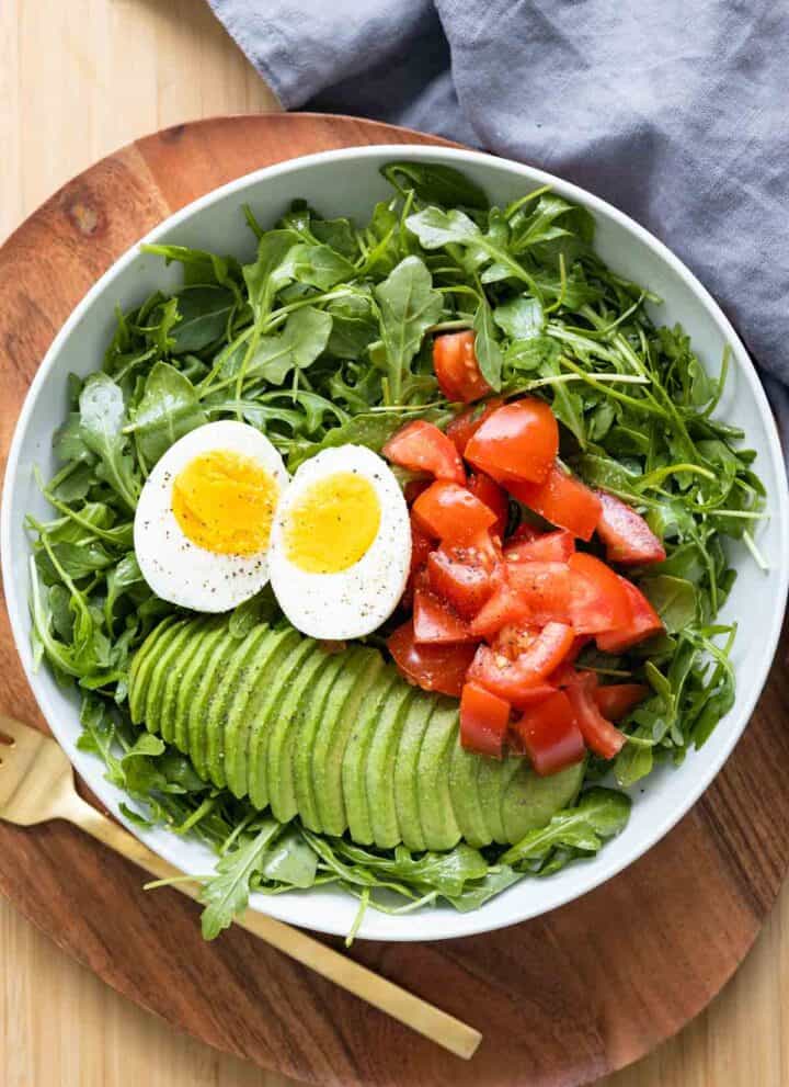 Breakfast salad made of arugula, tomato, avocado, and hard-boiled egg.