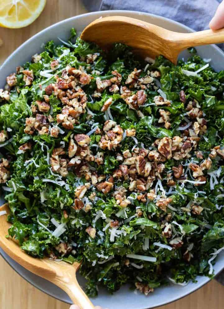 Kale Crunch Salad in a grey salad bowl with wooden spoons.