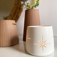 Candle Holders - In Stock & Ready to Ship Overview: Beautiful ceramic candle holders with a unique starburst design. Add light patterns and a fresh feel to your home with these modern candle holders. Durable stoneware with a white matte finish creates the perfect simple decor with a clean touch. Use a tea-light or small votive to light up your space and create a moody room. Details: 4"D x 3.5" H White Ceramic Matte Finish Starburst Design Hand Wash Candle not included Designed by Amy Hamley