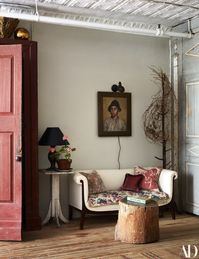 A stump table and an early-20th-century French settee in a dining area corner. A dried plant sculpture by Christopher Bassett wraps a vintage hat tree.