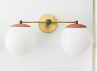 A colorful and bold take on classic globe sconce lighting. Our fun color combos will instantly add personality and elevate the interior design. This large fixture is great in traditional, mid-century, or designed for kids' interior bathroom design. Measurements & Information: 21" W, 11" L, 9" D glass diameter: 8" wall plate measurements: 5" x 1" depth Bulbs not included, recommend G16.5 or A19 E26 bulbs, max 75 W UL rated components Hardwired sconce that can be modified to be a plug in with