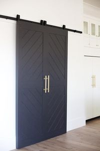 Chic kitchen features a walk-in pantry finished with black chevron sliding doors on rails.