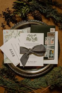 Evergreen winter wedding flat lay photo with pine cones and greens decorating the wedding invitations.