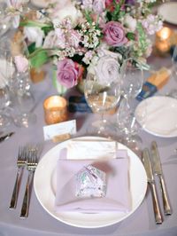 A place setting with lots of charming personal details, pastel lavender linen and napkins carry the pastel theme through to the low floral centerpieces filled with spring flowers in pale pink and purple shades.