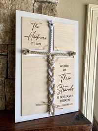 "Add a unique touch to your unity ceremony with our personalized \"Cord of three strands\" sign. It also makes a wonderful wedding gift, anniversary gift, or perfect for display on a table at a wedding or reception! This sign features engraved natural wood layered onto a beautifully stained board in the color of your choice. The stain you choose will appear as the background color for the cross as well as the framed border. Wall hardware included. *This sign comes in two sizes and is available i