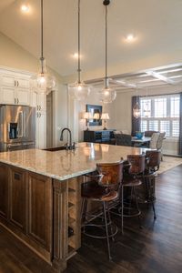 Experience the perfect blend of functionality and style in this Litchfield Craftsman kitchen. The warm wood tones, elegant cabinetry, and unique light fixtures reflect the timeless appeal of Craftsman design to create a kitchen that inspires and delights.  Download our free Craftsman True Design guide now to learn how to bring this classic style into your home!  #Craftsman #InteriorDesign #CustomHome #WayneHomes #CraftsmanDesign #DesignInspiration