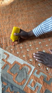 Painting on the mud of the Niger river to create this beautiful textile. Find our unique Mudcloth fashions on Etsy