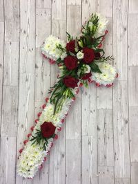 A crisp, red and white funeral cross. Based with white chrysanthemums with sprays of red Naomi rose and Veronica flower. Colours can easily be changed to reflect the personality of your loved one.  Made by Signature Flowers, Bicester   #cross #floralcross #funeral #funeralflowers #funeralcross #redroses #funeralflorist #casketadornment