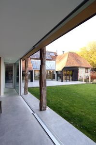 This modern #glazedextension provided a new home office to the traditional barn building. The modern extension used slim #slidingglassdoors to the entire garden facaing wall. The slim #glassdoors have a 21mm aluminium sightline with flush floor finishes. The working area can be completely connected to the garden when the doors are open or closed. Rustic timber posts line up with the door sightlines and match the traditional materials of the barn.