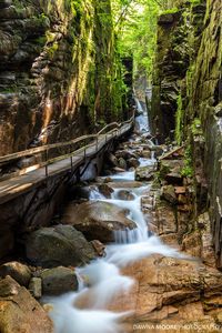 "The Flume was discovered in 1808 by 93-year-old “Aunt” Jess Guernsey when she accidently came upon it while fishing. She had trouble convincing her family of the marvelous discovery, but eventually persuaded others to come and see for themselves. At that time, a huge egg-shaped boulder hung suspended between the walls. The rock was 10 feet (3m) high and 12 feet (3.6m) long. A heavy rainstorm in June of 1883 started a landslide that swept the boulder from its place. It has never been fou...