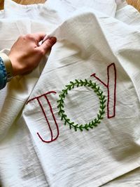 "JOY CHRISTMAS DECORATIVE FLOUR SACK TEA TOWEL This 100% cotton flour sack towel is the perfect Christmas kitchen accessory. It is carefully hand embroidered. There is something relaxing about simplicity in home decor. If you're looking for something minimalistic this holiday season, this flour sack towel is for you. Use this towel for your own holiday decorating or gift it to someone as a special gesture! Nothing says \"you're appreciated\" like a handcrafted gift! These flour sack towels are S