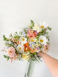 Anna’s bridal bouquet had white cosmos, pastel zinnias, peach foxglove, ranunculus, garden roses and more! Her textural, summer bridal bouquet was tied off with sage green handmade silk chiffon ribbon. Dream 2025 2026 2027 wedding flowers spring summer fall