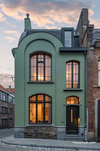 This dark green home features vertical grid windows that add a unique and stylish touch.