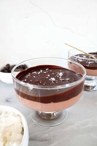 Chocolate cottage cheese mousse in a glass serving dish topped with a hard chocolate shell and sea salt. 