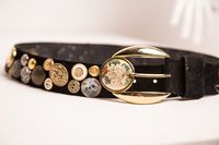 The most amazing, one of a kind button embellished leather belt with decorative buckle by Suzy Roher Accessories. This gorgeous piece is completely covered with many, many super unique buttons! The buckle of this belt features a large rose medallion.   By far, the coolest belt I've ever seen! Size Large; Fits up to a 32 inch waist. FREE SHIPPING TO USA AND CANADACanadians shop DUTY FREE