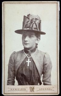 Betsy Caspara Fabricius (b. Kallevig) was born in Norway in 1868. Here she is photographed in the late 1880s wearing a tall hat and a striped bodice.The photo is available in high quality in our website and it is free to use with us listed as a source.