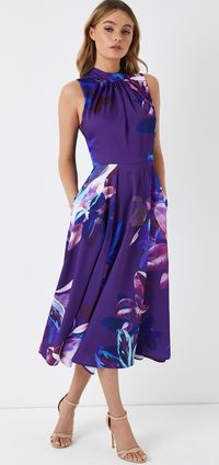 Purple floral Midi Dress. You'll be sure to receive loads of compliments at Royal Ascot with this bold floral dress. With hues of purple, blue pink and cream, this dress is the perfect summer racing dress, and with lot's of choices you can go for for your Ascot Hat. For lot's of ideas, and outfit inspiration for a day at the Races, read our blog on all the best dresses for Royal Ascot. What to wear to Royal Ascot. Summer fashion. #royalascot #fashion #fashionista #ascot #summerfashion.