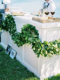 A perfect simple decoration for an outdoor garden wedding, the white bar decorated with a lush green garland draped across the front.