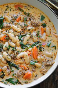 sausage white bean soup with carrots and spinach - in a white bowl.