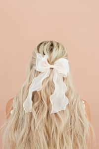 Complete your bridal look with our Pearlescent Bow. This simplistic yet elegant bow adds a feminine touch to any hairstyle, perfect for any bridal event. Details: Cream color with a pearlescent shine Bow width 6.25 inches, height approximately 10 inches- each bow will slightly vary due to their handmade nature Metal Barrette to secure into hair is 4 inches wide Edging is finished Final Sale