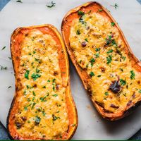 Butternut squash is filled with hearty grains and a cheesy Alfredo sauce and then baked again until melty and golden brown. Serve as a hearty main dish for the holidays!  #rainbowplantlife #butternutsquash #veganrecipes #vegancomfortfood