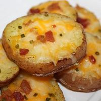 Cheesy Bacon Potato Rounds. Ingredients: 4 baking potatoes, cut into 1/2 inch slices; 1/4 cup melted butter; 8 slices bacon - cooked and crumbled; 8 ounces shredded Cheddar cheese; 1/2 cup chopped green onions. Directions: Preheat oven to 400 degrees F. Brush both side of potato slices with butter; place them on an ungreased cookie sheet. Bake for 30 to 40 minutes or until lightly browned on both sides, turning once. When potatoes are ready, top with bacon, cheese, and green onion; continue b...