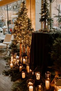 The entrance at Axis Pioneer square is decorated with lanterns and hurricane candles along side tall evergreen trees filling the space with a cozy glow for a winter wedding in Seattle.