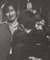 Sirus Black giving his godson Harry Potter a hug, while Remus Lupin looks on