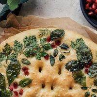 lily morello • flatlays & food on Instagram: "Here is what my wreath focaccia art looked like after baking! You can see the pre-bake version with the fresh herbs in my previous post; I used lemon balm, mint, parsley, dill, and pomegranate arils, then sprinkled it with kosher salt before popping it in the oven. Simple, but so delicious to tuck into some fresh homemade bread while it is still warm. ⁣
⁣
I am so happy with how well the leaves kept their shape and color after baking. I was honestly beaming with pride as I took this out of the oven (usually it’s the complete opposite!)⁣
⁣
I attempted a focaccia wreath last year too and you can swipe to see that. I got so much more practice this year, decorating baked goods with natural herbs and flowers, and I hope you’ll agree that my technique