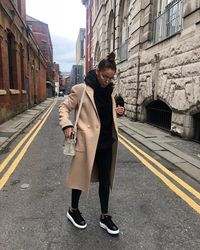 black hoodie and black leggings and nike sneakers and camel trenchcoat Minimalistic Outfit | Outfit Ideas | Nutrition Stripped #nutritionstripped #minimalistic #minimalisticoutfit #trendyoutfit #minimalisticoutfitideas