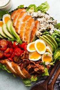 homemade chicken cobb salad with ranch dressing by The Modern Proper. Crispy chicken, crumbled bacon, creamy avocado, jammy eggs and sharp blue cheese all on a bed of Romaine topped with a pour of homemade buttermilk dressing.