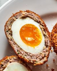 closeup of a scotch egg, sliced to reveal yolk