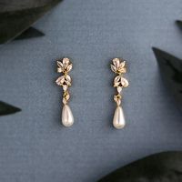 A single ivory teardrop pearl hangs from a delicate cluster of CZ jewels. These wedding day earrings are delightfully elegant. They are about 1.25 inches long and .25 inches wide, lead and nickel free, grade AAA CZ stones. #earrings #weddingaccessories