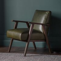 Experience the epitome of timeless elegance and modern comfort with the Sutton Armchair.  Crafted with sturdy wooden legs and upholstered in luxurious green leather, this mid-century style chair transforms any space with its sophisticated charm. Designed for both comfort and durability, it features a supportive seat and backrest for long-lasting relaxation.  Combining classic design with contemporary comfort, the Sutton Armchair is perfect for those who value aesthetics and functionality. Elevate your home decor with this stunning piece, ideal for your living room or study, and enjoy a blend of style and comfort. Item dimensions: 81.5cm (H) x 61cm (W) x 73cm (D) Seat height – 47cm