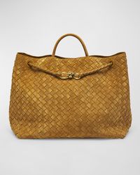 "Find BOTTEGA VENETA Andiamo Tote Bag on Editorialist. The Bottega Veneta Andiamo tote bag is crafted from intricately woven suede and leather. The bag features a rolled top handle, a shoulder strap, and a knotted drawstring closure. The interior includes one zip pocket and two slip pockets. It measures approximately 13.8\"H x 16.5\"W x 7.1\"D. Made in Italy."