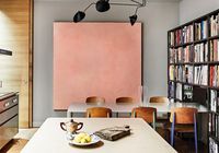 Kitchen/dining space with large art, a wall of books, and a dining table