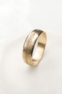 This tree wedding ring is handcrafted in 14k solid gold.  The nature inspired wedding ring has a tree engraved on the surface.  Each ring is one-of-a-kind, ensuring every person has their very own unique ring.  The gold tree ring has faceted edges and a matte finish, with a high polished edge.  The rustic gold ring makes a perfect gift for a nature lover or for a unique mens or woman's wedding ring.   This tree ring is available in solid 14k or 18k yellow, white, or rose gold.  It's also availab