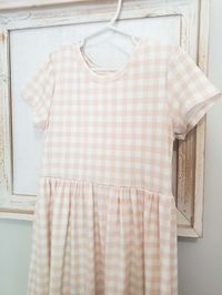 Adorable soft blush gingham dress. A sweet slightly gathered sleeve and simple skirt. Length is customizable, choose mid-calf or maxi length. This easy care dress is made from mini rib knit fabric for a smooth, cool feel. This dress is versatile and can be dressed up or down. Quick, easy summer wear and handmade to last! This simple style can be made for baby to tween! poly 92% spandex 8% Sizing is generous on this style! Item is made to order. Turn around time is 3-4 weeks.