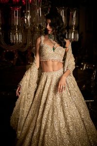 This lehenga set features very intricate embroidery in silver french notes, pearl and crystal. The lehenga ghera shows cut work. It is paired with scalloped dupatta with crystal tassels on all four sides. The bottom of the blouse too shows delicate crystal tassels. DELIVERY TIMEPlease allow 8-12 weeks for your outfit to arrive. FABRIC DETAILSLehenga - Net / Dupatta - Net Professional cleaning only.