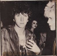 Steve Jones and Billy Idol sharing a drink in 1978 as Bebe Buell photobombs in the background