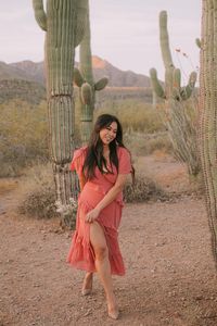 She is wearing a pink flowy dress for her engagement session in Arizona. A beautiful dress during spring and in a desert.